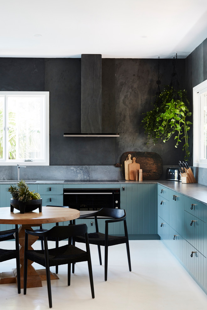 Design ideas for a mid-sized tropical l-shaped eat-in kitchen in Sydney with an undermount sink, flat-panel cabinets, quartz benchtops, grey splashback, slate splashback, stainless steel appliances, painted wood floors, white floor, grey benchtop and blue cabinets.