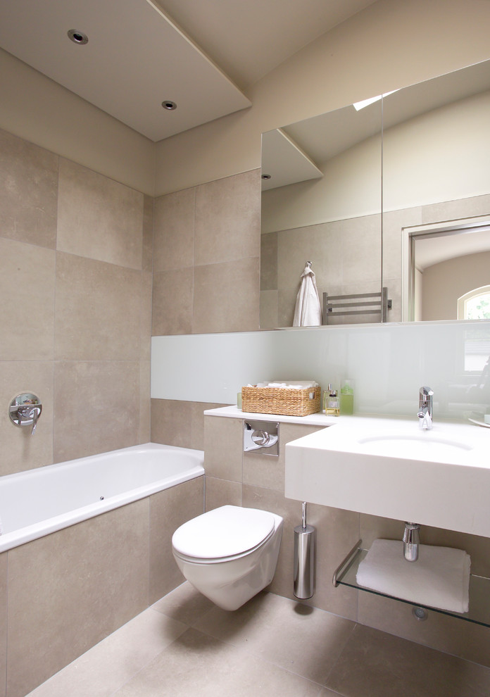 Contemporary bathroom in Berkshire with an undermount sink, a drop-in tub, beige tile, beige walls and a wall-mount toilet.