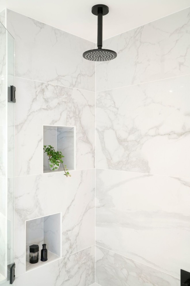 This is an example of a mid-sized contemporary bathroom in London with flat-panel cabinets, white cabinets, a drop-in tub, a curbless shower, a wall-mount toilet, porcelain tile, porcelain floors, a wall-mount sink and granite benchtops.