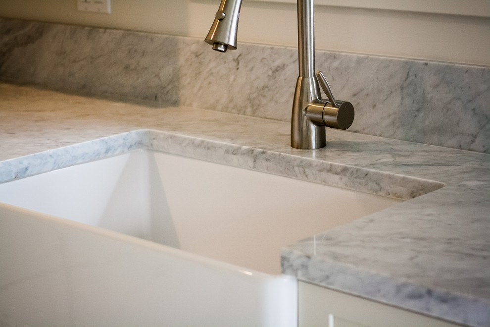 Example of a transitional kitchen design in San Francisco with a farmhouse sink, white cabinets and marble countertops