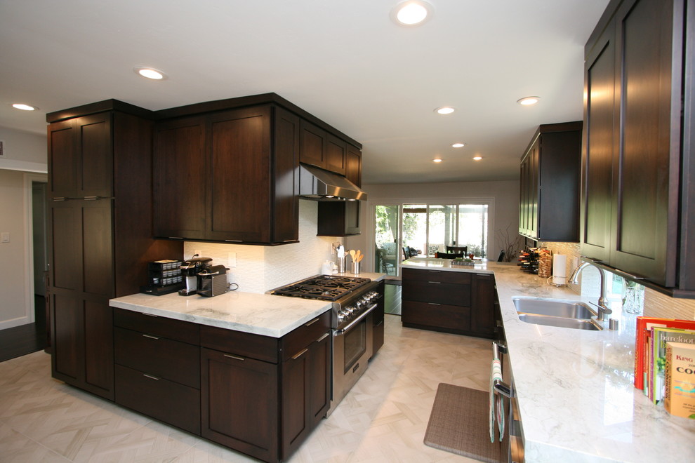 Mid-sized transitional l-shaped porcelain tile kitchen photo in Orange County with a double-bowl sink, recessed-panel cabinets, dark wood cabinets, quartzite countertops, white backsplash, glass tile backsplash, stainless steel appliances and no island