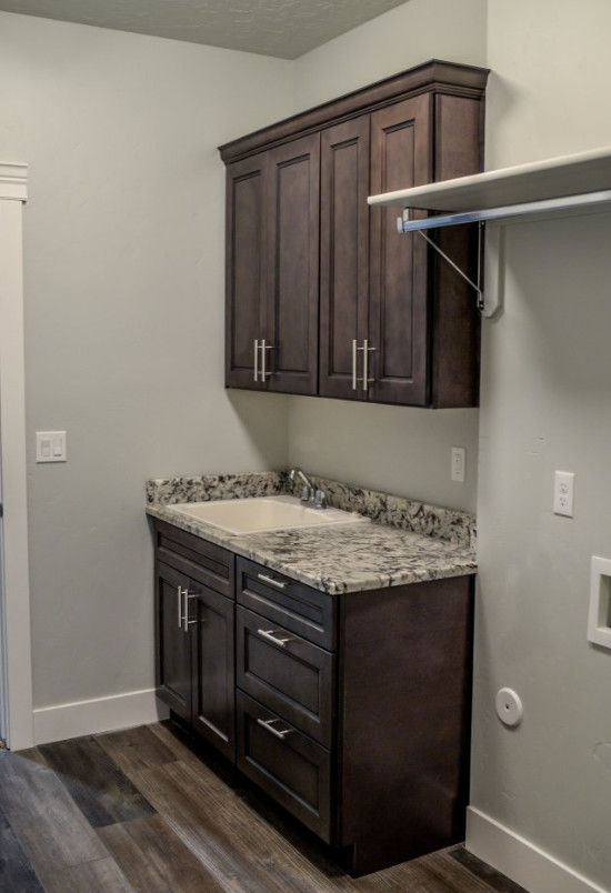 Design ideas for a small single-wall utility room in Other with a single-bowl sink, shaker cabinets, brown cabinets, granite benchtops, grey walls, laminate floors and multi-coloured benchtop.