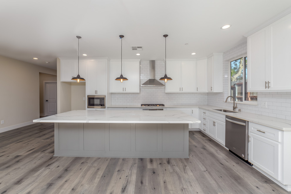 Design ideas for a mid-sized traditional u-shaped open plan kitchen in Sacramento with an undermount sink, shaker cabinets, white cabinets, quartzite benchtops, white splashback, subway tile splashback, stainless steel appliances, laminate floors, with island, grey floor and white benchtop.