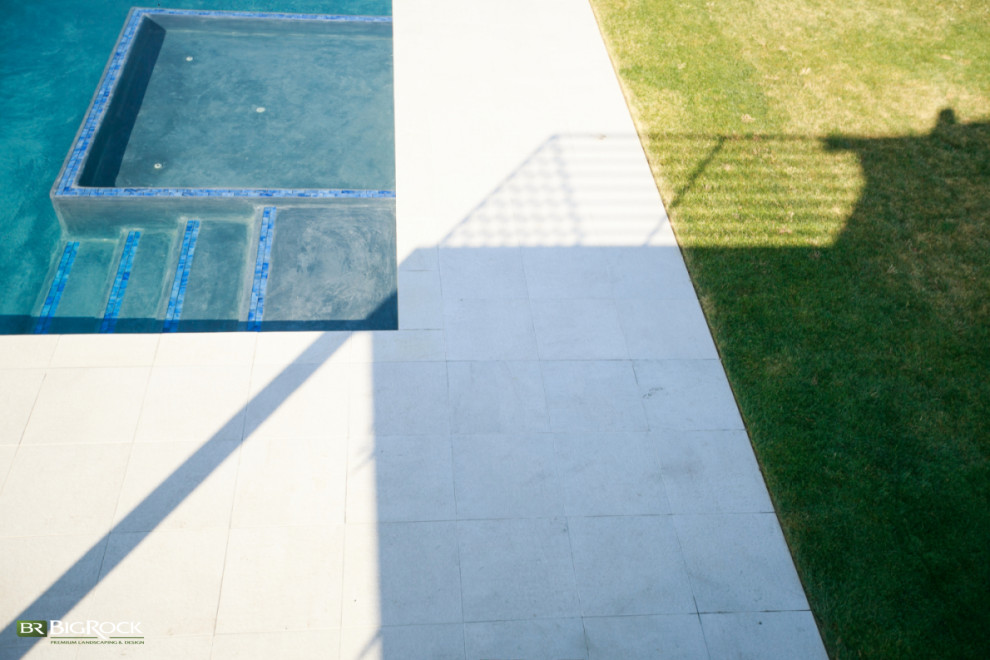 На фото: прямоугольный ландшафтный бассейн на заднем дворе в современном стиле с мощением тротуарной плиткой с