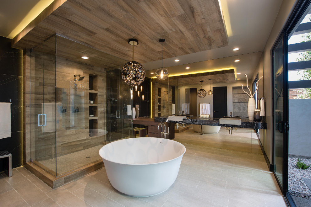 Photo of a large contemporary master bathroom in Las Vegas with flat-panel cabinets, dark wood cabinets, a freestanding tub, gray tile, wood-look tile, a vessel sink, grey floor, a hinged shower door, black benchtops, a built-in vanity, granite benchtops and a double vanity.