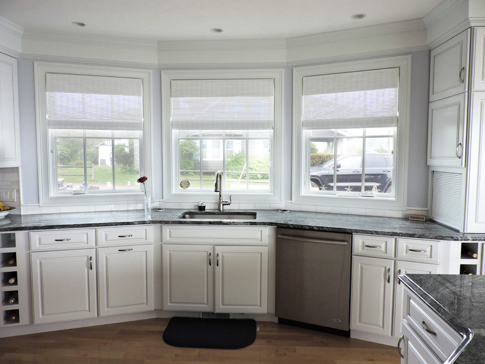 Eat-in kitchen - large coastal u-shaped light wood floor and beige floor eat-in kitchen idea with an undermount sink, raised-panel cabinets, white cabinets, granite countertops, white backsplash, subway tile backsplash, stainless steel appliances, an island and gray countertops
