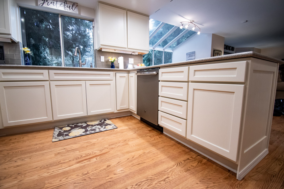 Inspiration for a transitional u-shaped medium tone wood floor open concept kitchen remodel in Seattle with an undermount sink, shaker cabinets, white cabinets, quartz countertops, gray backsplash, glass tile backsplash, stainless steel appliances, a peninsula and multicolored countertops