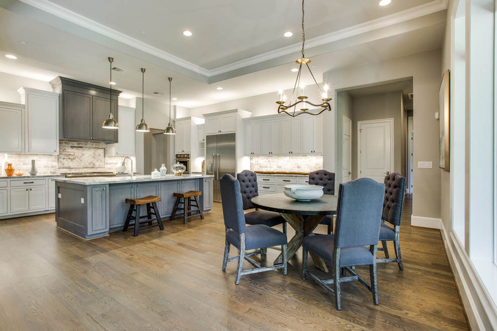 This is an example of a large transitional l-shaped eat-in kitchen in Houston with a farmhouse sink, shaker cabinets, white cabinets, marble benchtops, brown splashback, stone tile splashback, stainless steel appliances, medium hardwood floors and with island.