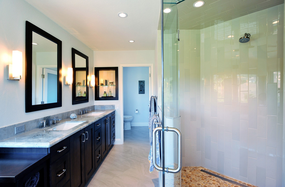 This is an example of a large beach style master bathroom in Los Angeles with an undermount sink, raised-panel cabinets, dark wood cabinets, granite benchtops, a corner shower, a two-piece toilet, gray tile, porcelain tile, blue walls and porcelain floors.