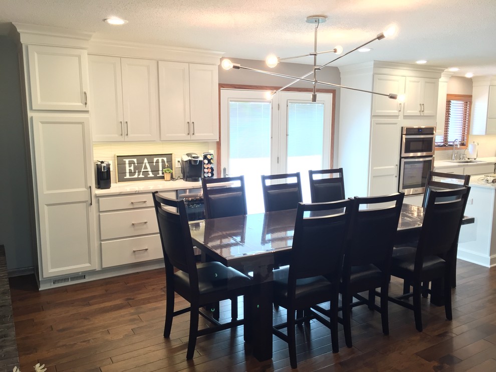 Large transitional l-shaped dark wood floor eat-in kitchen photo with an undermount sink, flat-panel cabinets, white cabinets, quartz countertops, white backsplash, ceramic backsplash, stainless steel appliances and an island