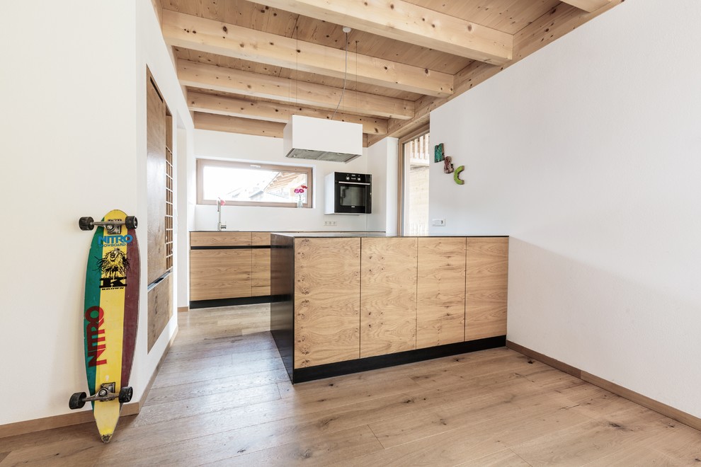 This is an example of a small country galley open plan kitchen in Munich with an undermount sink, flat-panel cabinets, medium wood cabinets, medium hardwood floors and with island.
