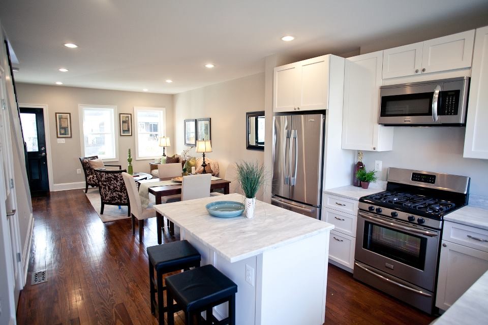 Photo of a mid-sized traditional l-shaped eat-in kitchen in DC Metro with recessed-panel cabinets, white cabinets, marble benchtops, stainless steel appliances, medium hardwood floors and with island.