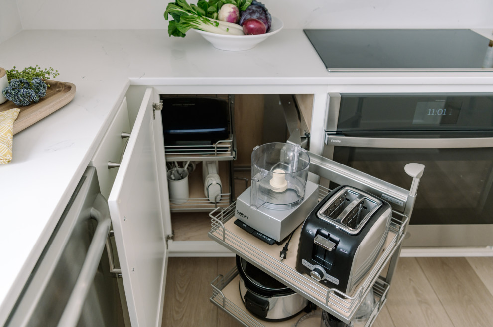 Example of a large transitional l-shaped laminate floor and brown floor eat-in kitchen design with an undermount sink, shaker cabinets, white cabinets, quartz countertops, white backsplash, quartz backsplash, stainless steel appliances, an island and white countertops