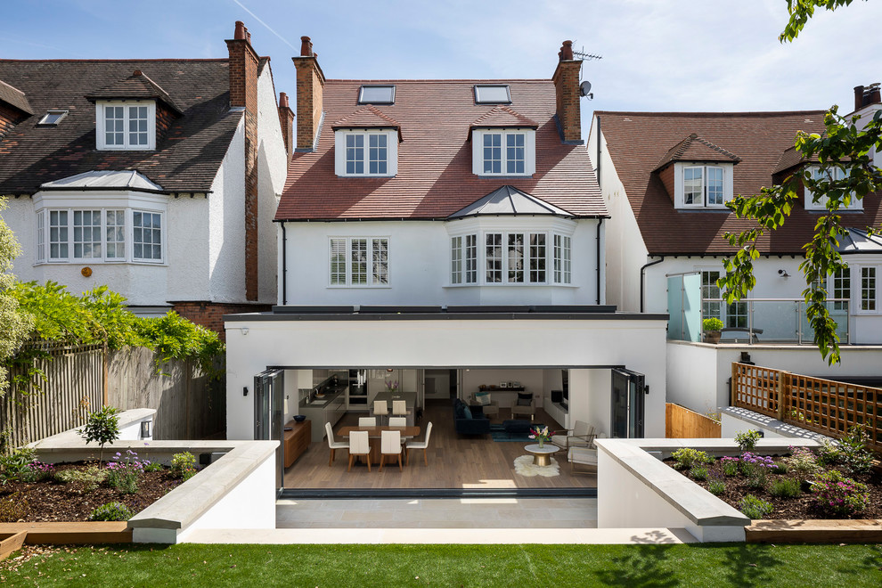 Design ideas for a large modern three-storey stucco multi-coloured house exterior in London with a gable roof, a shingle roof and a red roof.