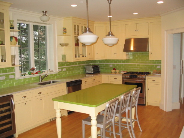 Inspiration for a mid-sized eclectic l-shaped eat-in kitchen in Boston with an undermount sink, recessed-panel cabinets, yellow cabinets, green splashback, ceramic splashback, stainless steel appliances, light hardwood floors and no island.