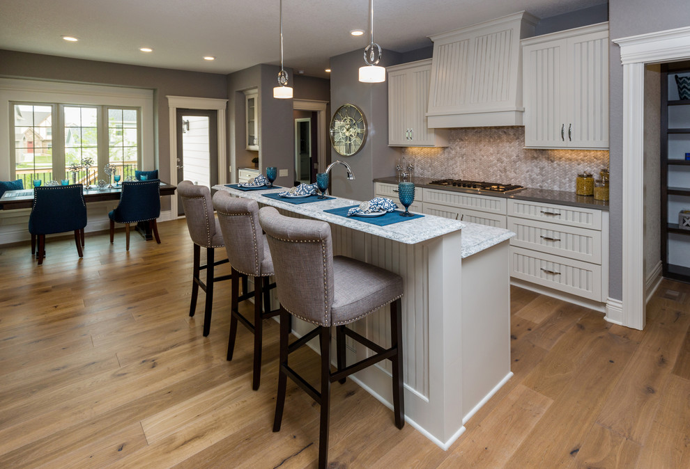Kitchen pantry - transitional l-shaped kitchen pantry idea with an undermount sink, beaded inset cabinets, white cabinets, quartz countertops, beige backsplash, stone tile backsplash, stainless steel appliances and an island
