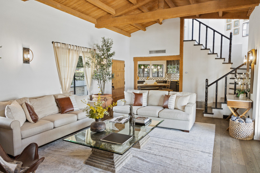 This is an example of a mediterranean living room in Los Angeles with white walls, dark hardwood floors, brown floor, exposed beam, vaulted and wood.