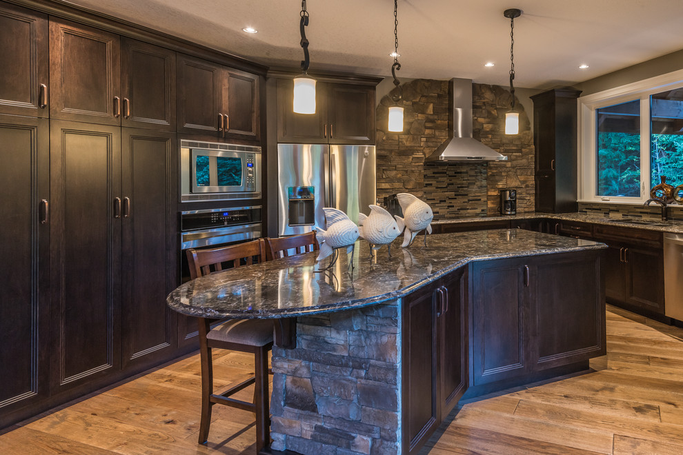 Example of a mid-sized mountain style u-shaped medium tone wood floor eat-in kitchen design with a drop-in sink, beaded inset cabinets, dark wood cabinets, granite countertops, multicolored backsplash, matchstick tile backsplash, stainless steel appliances and an island