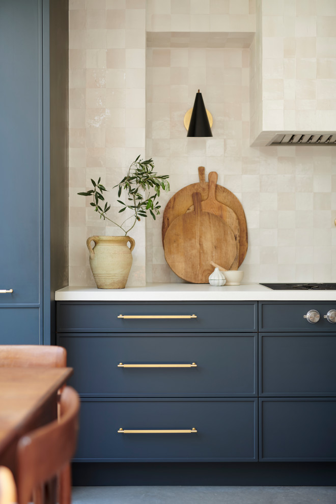 Design ideas for a medium sized nautical l-shaped kitchen/diner in London with a belfast sink, beaded cabinets, blue cabinets, concrete worktops, white splashback, porcelain splashback, black appliances, concrete flooring, an island, grey floors, white worktops and a timber clad ceiling.