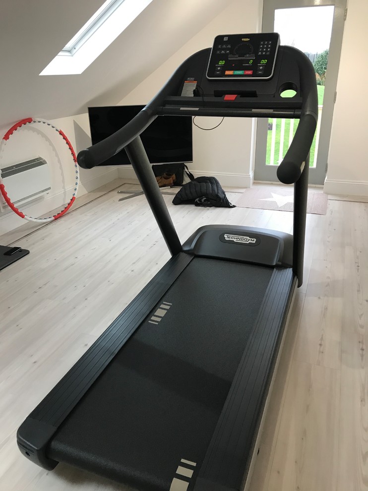 Photo of a small contemporary home weight room in London with beige walls, light hardwood floors and white floor.