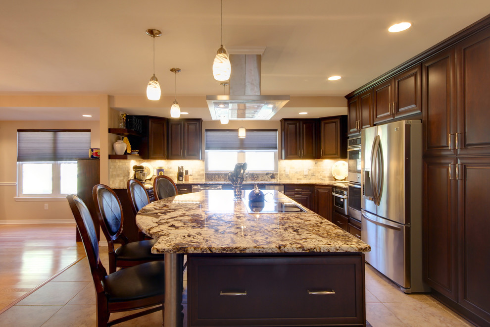 Example of a large transitional l-shaped porcelain tile eat-in kitchen design in Miami with an undermount sink, raised-panel cabinets, dark wood cabinets, granite countertops, beige backsplash, stone tile backsplash, stainless steel appliances and an island