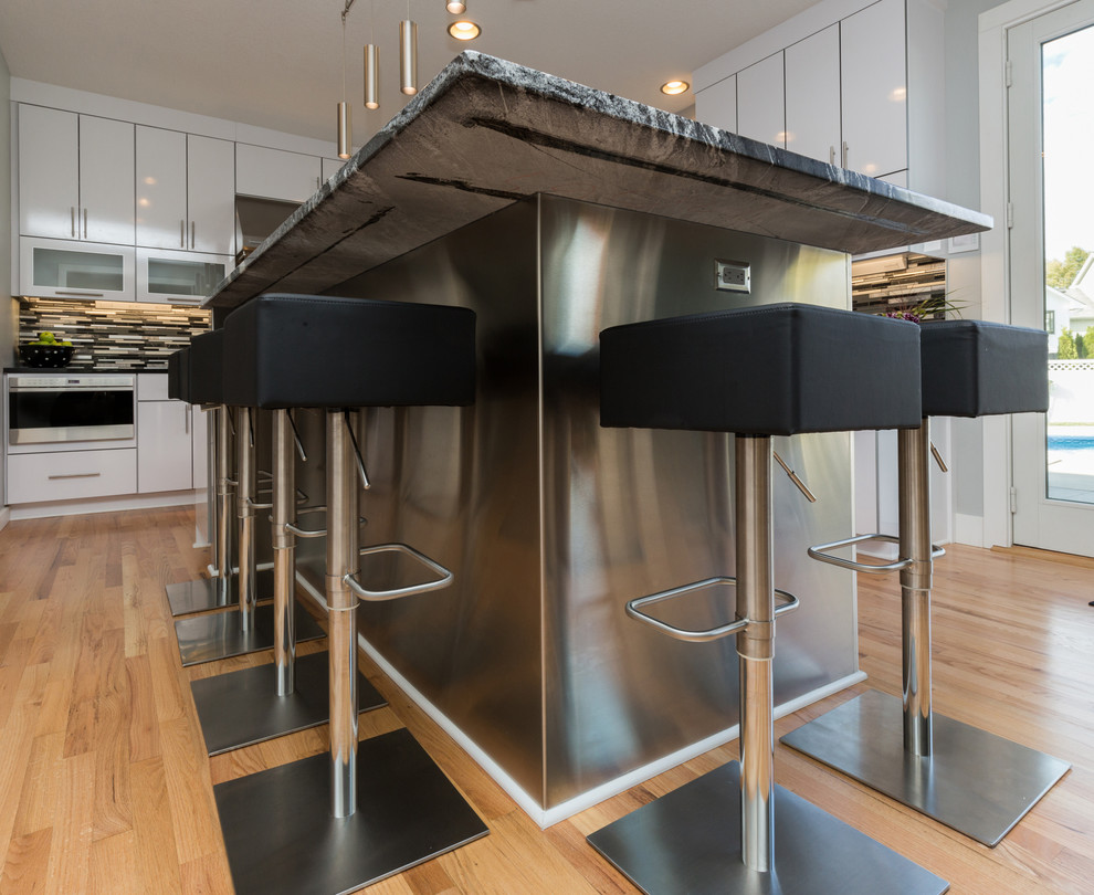 Inspiration for a large contemporary u-shaped light wood floor open concept kitchen remodel with an undermount sink, flat-panel cabinets, white cabinets, granite countertops, multicolored backsplash, mosaic tile backsplash, stainless steel appliances and an island