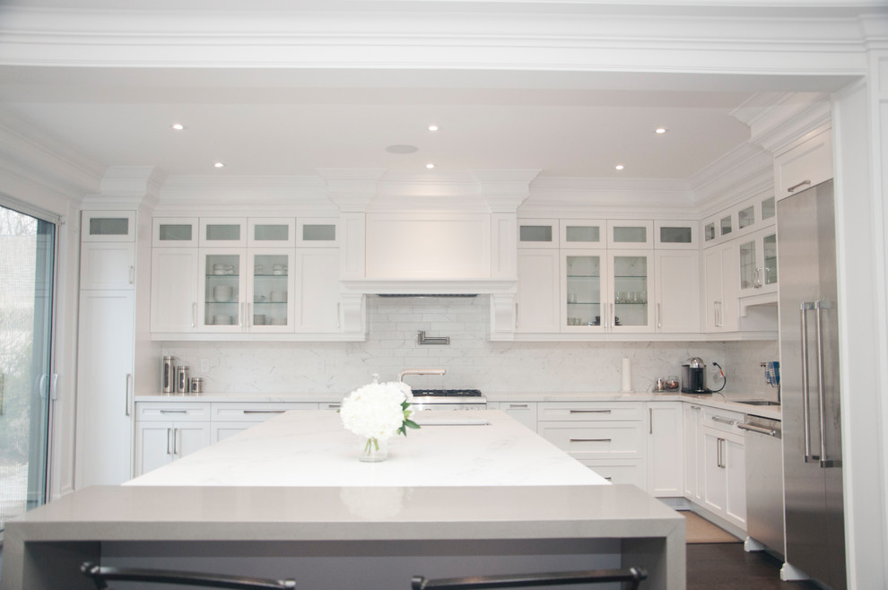 Inspiration for a large transitional l-shaped dark wood floor and brown floor enclosed kitchen remodel in Toronto with an undermount sink, shaker cabinets, white cabinets, quartz countertops, white backsplash, marble backsplash, stainless steel appliances, an island and white countertops