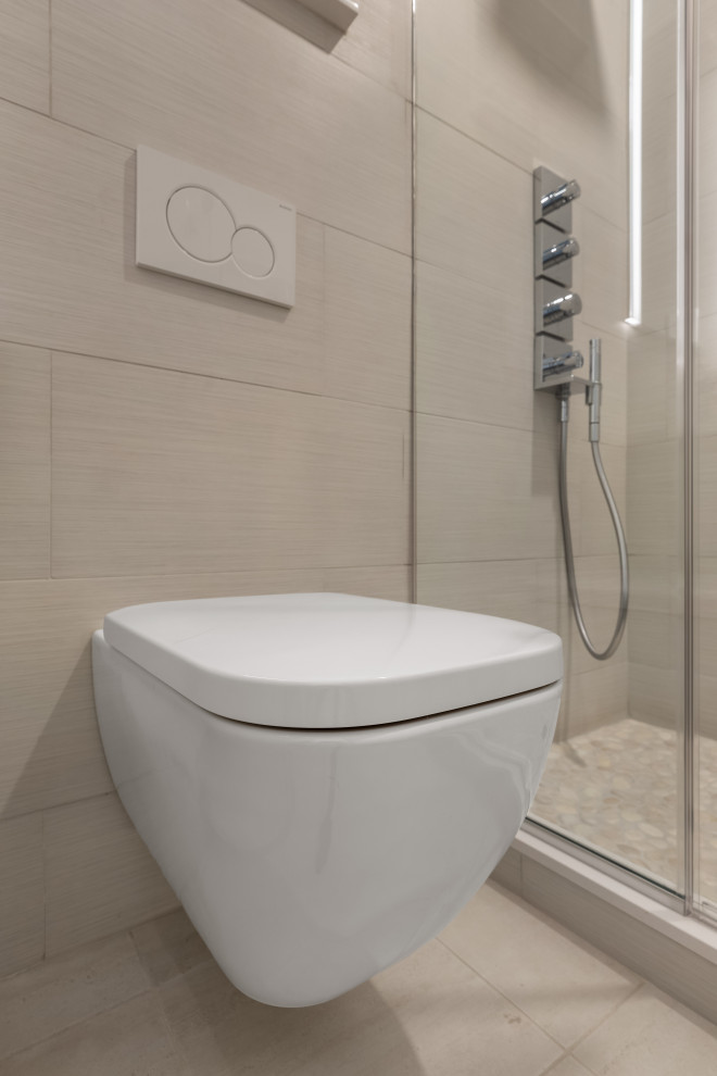 This is an example of a medium sized modern ensuite bathroom in New York with recessed-panel cabinets, grey cabinets, an alcove shower, a wall mounted toilet, beige tiles, ceramic tiles, ceramic flooring, a submerged sink, engineered stone worktops, beige floors, a hinged door, white worktops, a shower bench, a single sink and a freestanding vanity unit.