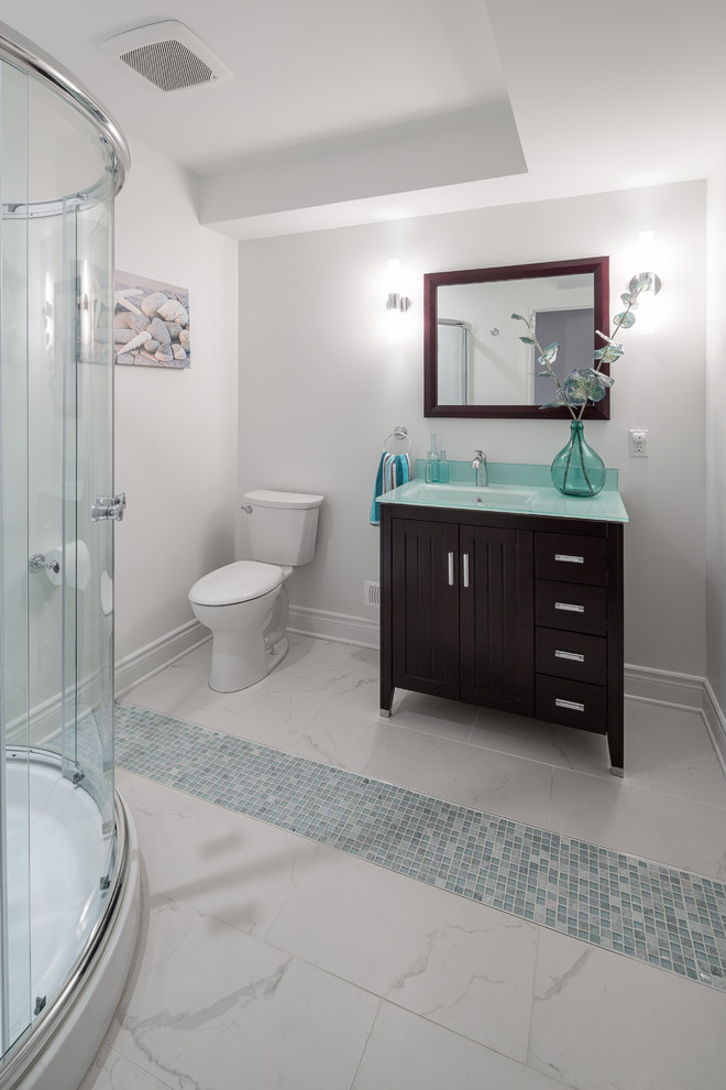 This is an example of a mid-sized contemporary 3/4 bathroom in Ottawa with beaded inset cabinets, dark wood cabinets, a corner shower, a two-piece toilet, white tile, glass tile, white walls, marble floors, an integrated sink and glass benchtops.