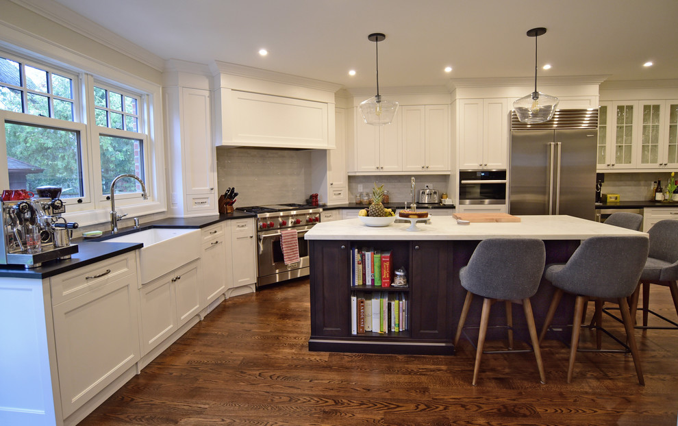 Inspiration for a transitional kitchen remodel in Toronto with recessed-panel cabinets, white cabinets, porcelain backsplash, stainless steel appliances and an island