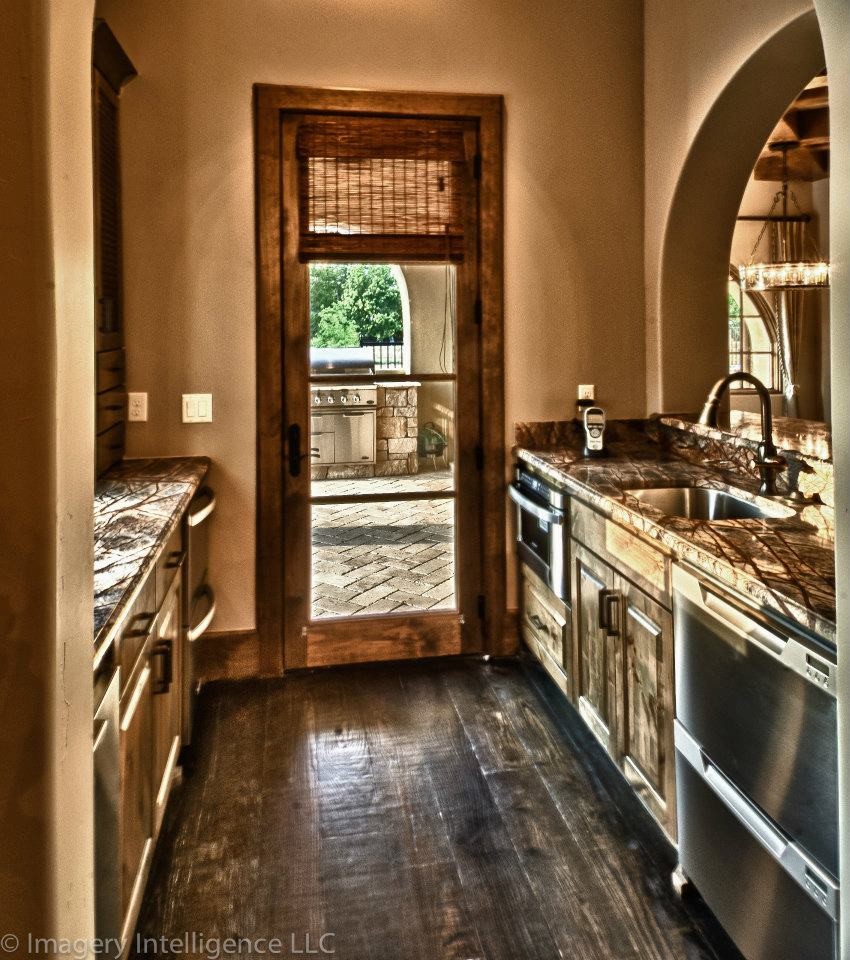 This is an example of a mediterranean galley wet bar in Dallas with an undermount sink, medium wood cabinets, granite benchtops and dark hardwood floors.