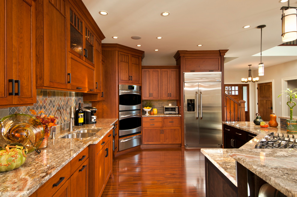 Design ideas for a large traditional l-shaped eat-in kitchen in Boston with recessed-panel cabinets, granite benchtops, multi-coloured splashback, stainless steel appliances, with island, brown floor, an undermount sink, medium wood cabinets, slate splashback, medium hardwood floors and multi-coloured benchtop.