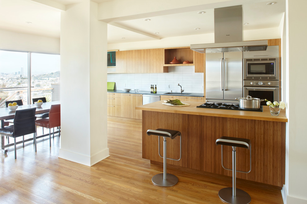 Modern galley eat-in kitchen in San Francisco with wood benchtops, flat-panel cabinets, light wood cabinets and stainless steel appliances.
