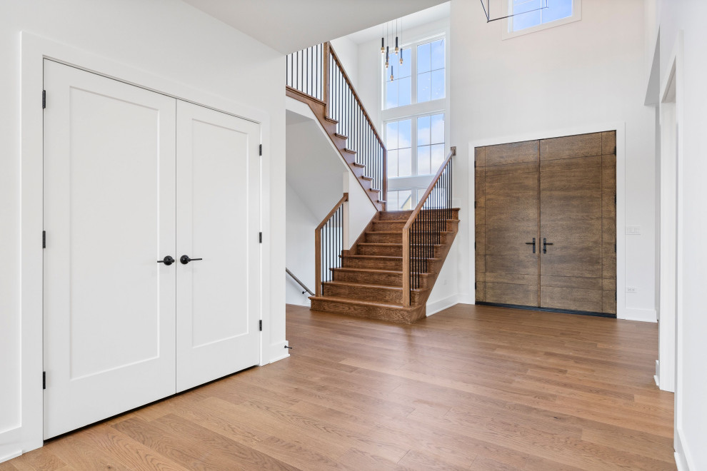 Example of a large transitional medium tone wood floor, brown floor, vaulted ceiling and shiplap wall entry hall design in Chicago with white walls and a dark wood front door