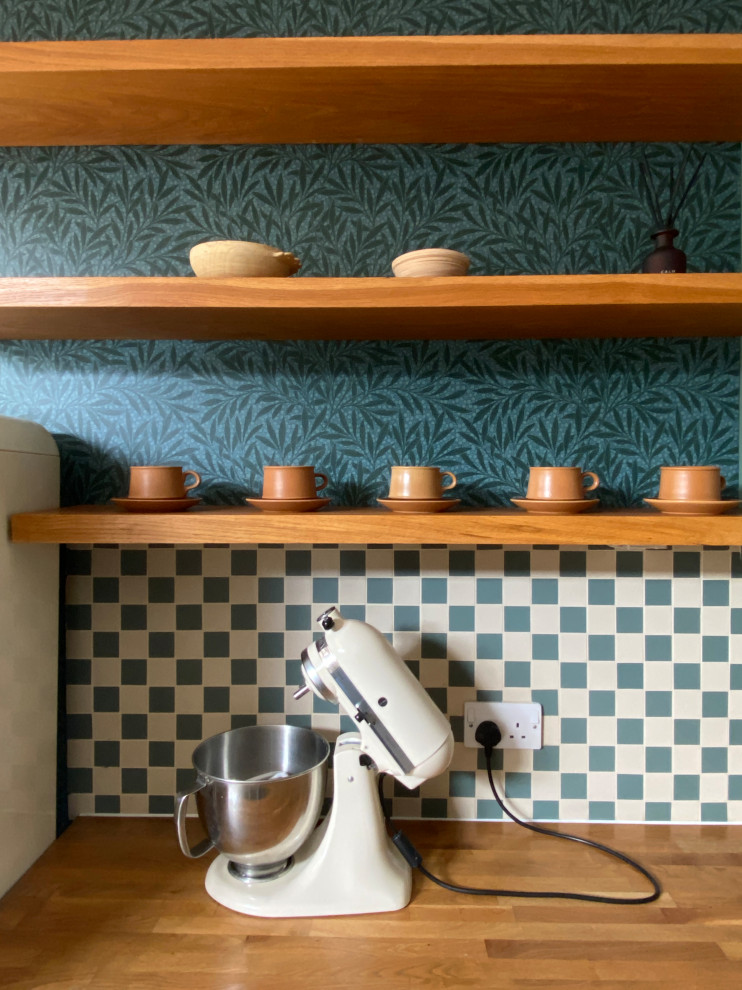 Mid-sized arts and crafts u-shaped eat-in kitchen in London with a farmhouse sink, shaker cabinets, green cabinets, wood benchtops, multi-coloured splashback, ceramic splashback, coloured appliances, cement tiles, with island, brown floor and beige benchtop.