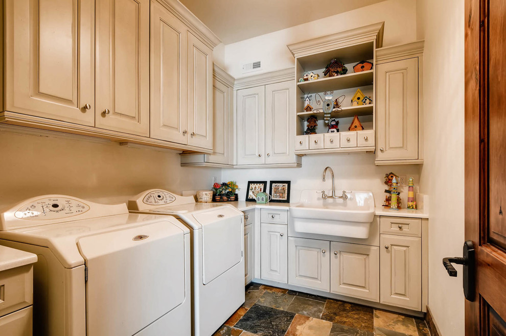 Photo of a large traditional l-shaped dedicated laundry room in Denver with an utility sink, raised-panel cabinets, beige cabinets, quartz benchtops, beige walls, slate floors, a side-by-side washer and dryer and multi-coloured floor.