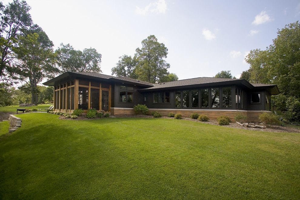 Large midcentury one-storey black exterior in Minneapolis with mixed siding and a hip roof.