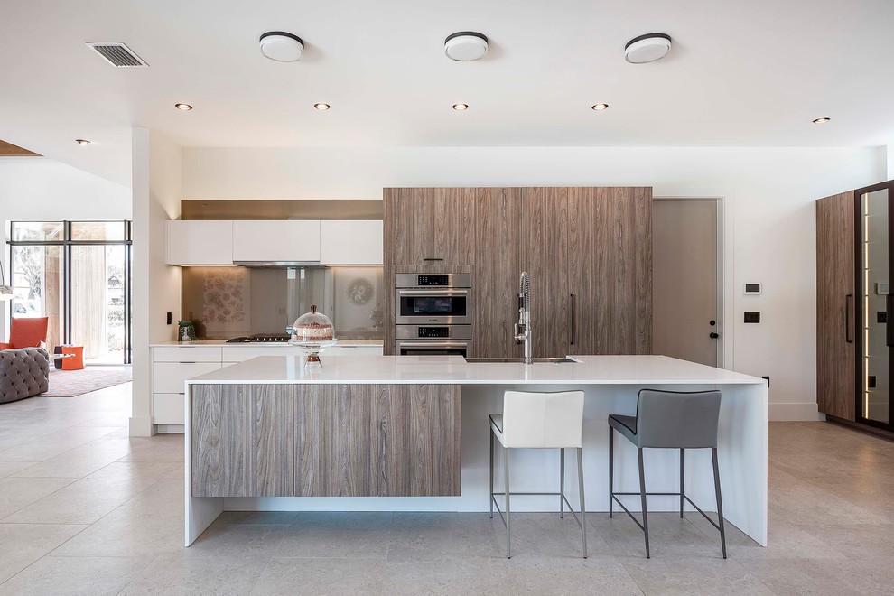 Large trendy galley beige floor open concept kitchen photo in Orlando with a farmhouse sink, marble countertops, stainless steel appliances, an island, white countertops, flat-panel cabinets, white cabinets, beige backsplash and glass sheet backsplash