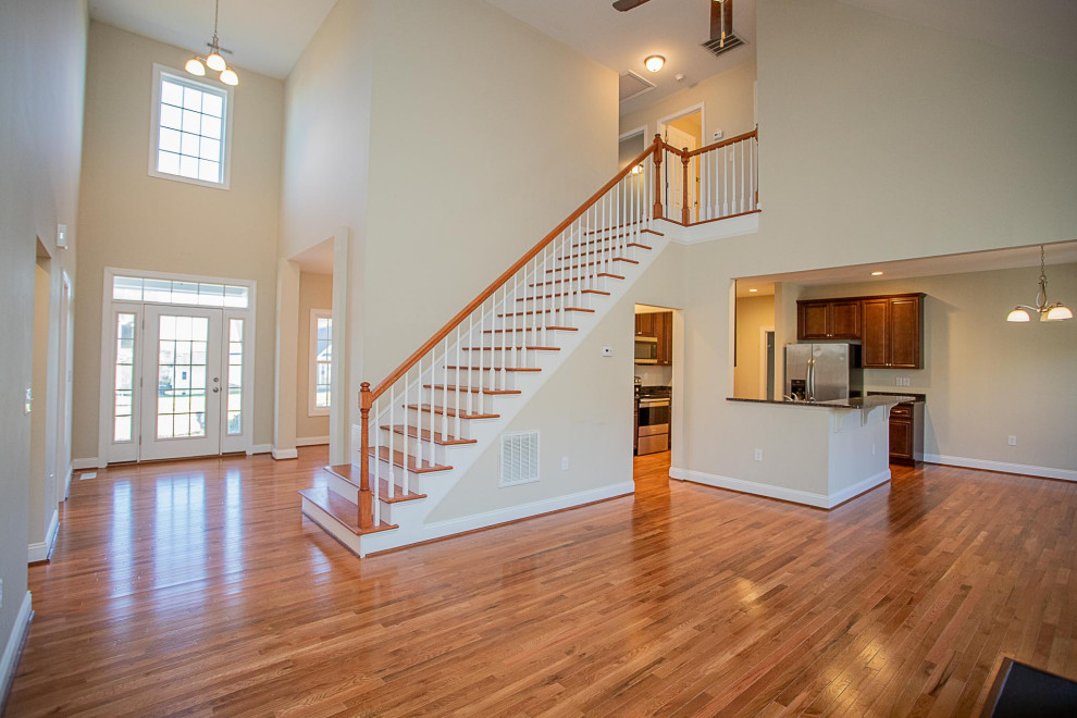 Photo of a large arts and crafts foyer in Other with white walls, medium hardwood floors, a pivot front door, a glass front door, brown floor and vaulted.