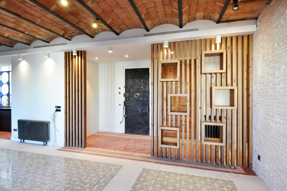 Cette image montre une grande entrée minimaliste avec un couloir, un mur blanc, un sol en carrelage de céramique, une porte simple, une porte métallisée, un sol rouge, un plafond voûté et un mur en parement de brique.