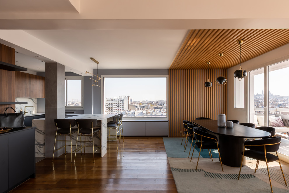 Идея дизайна: огромная гостиная-столовая с синими стенами, светлым паркетным полом, коричневым полом и панелями на стенах без камина