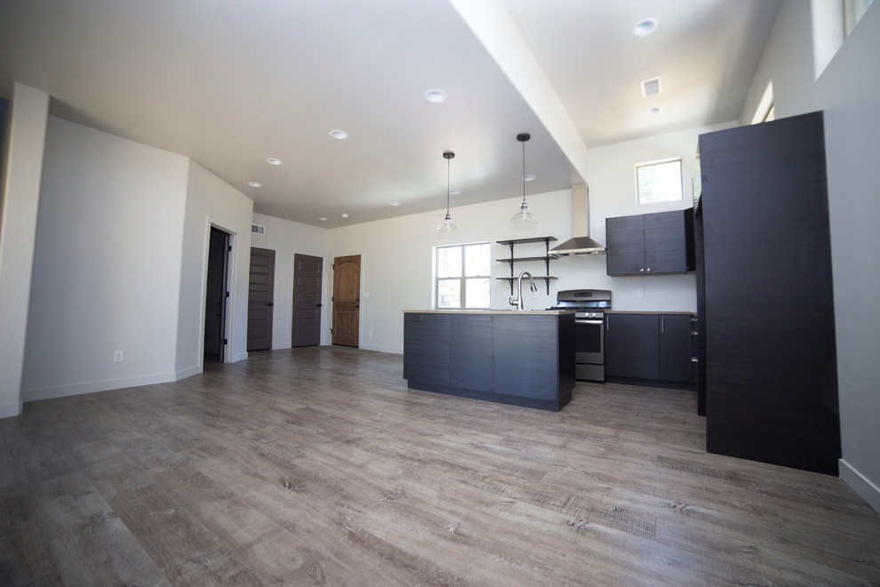 Inspiration for a small rustic medium tone wood floor open concept kitchen remodel in Phoenix with flat-panel cabinets, black cabinets, wood countertops and an island