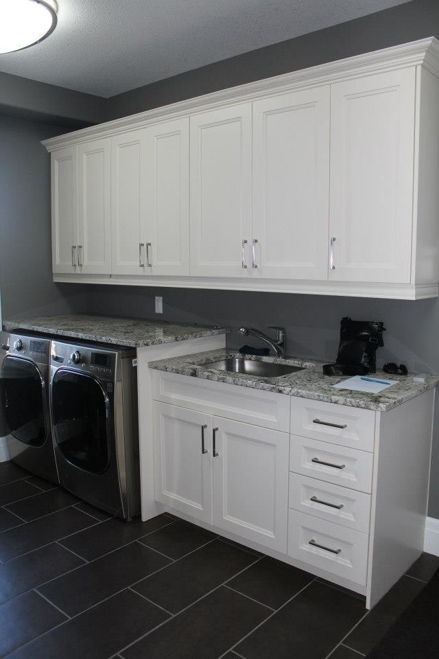 Photo of a transitional laundry room in Toronto with an undermount sink, white cabinets, granite benchtops, grey walls and a side-by-side washer and dryer.