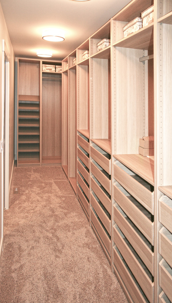Photo of a small transitional gender-neutral walk-in wardrobe in Calgary with flat-panel cabinets, light wood cabinets and carpet.