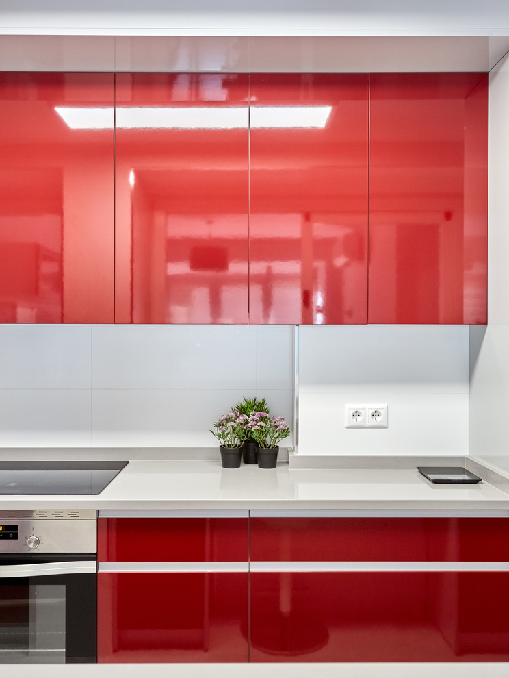 Inspiration for a small modern galley open plan kitchen in Other with a drop-in sink, flat-panel cabinets, red cabinets, white splashback, porcelain splashback, stainless steel appliances, porcelain floors, no island, grey floor and grey benchtop.