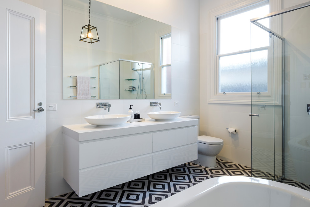 Inspiration for a contemporary 3/4 bathroom in Adelaide with flat-panel cabinets, white cabinets, a freestanding tub, a corner shower, white tile, white walls, cement tiles, a vessel sink, black floor and a hinged shower door.