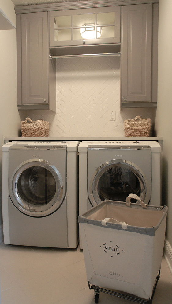 This is an example of a small traditional single-wall dedicated laundry room in Ottawa with raised-panel cabinets, grey cabinets, quartz benchtops, grey walls, porcelain floors and a side-by-side washer and dryer.