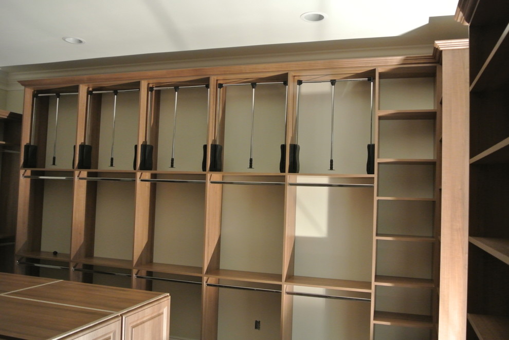 This is an example of a large traditional gender neutral dressing room in Miami with raised-panel cabinets, medium wood cabinets and travertine flooring.