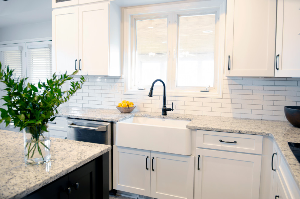 Mid-sized country l-shaped eat-in kitchen in Louisville with a farmhouse sink, shaker cabinets, white cabinets, granite benchtops, white splashback, ceramic splashback, stainless steel appliances, ceramic floors, with island, beige floor and white benchtop.