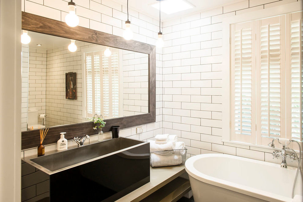 Huge transitional subway tile and white tile ceramic tile freestanding bathtub photo with white cabinets, a wall-mount toilet, white walls, concrete countertops, a vessel sink and gray countertops